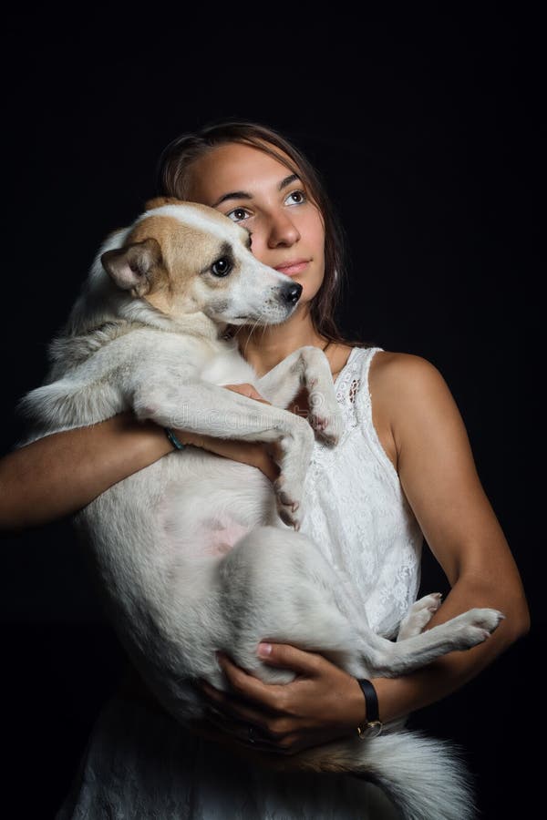 Menina bonita que guarda um cão bonito em seus braços imagem de stock royalty free Menina bonita que guarda um cão bonito em seus braços imagem de stock royalty free