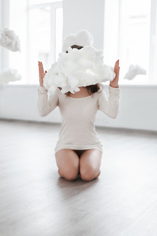 Menina bonita que senta-se no assoalho nas nuvens fotos de stock Menina bonita que senta-se no assoalho nas nuvens fotos de stock