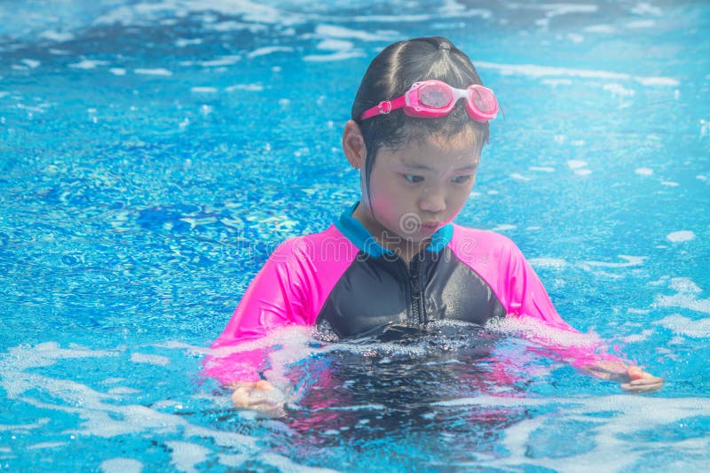 A menina bonito asi?tica da felicidade tem o sentimento engra?ado e aprecia-o na piscina foto de stock A menina bonito asi?tica da felicidade tem o sentimento engra?ado e aprecia-o na piscina foto de stock