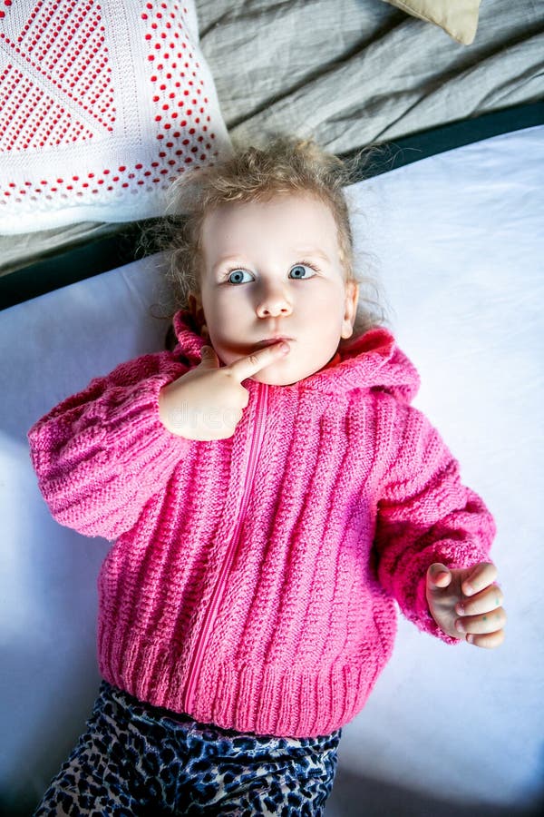 A menina bonito de olhos azuis em uma camiseta cor-de-rosa pensa imagens de stock A menina bonito de olhos azuis em uma camiseta cor-de-rosa pensa imagens de stock