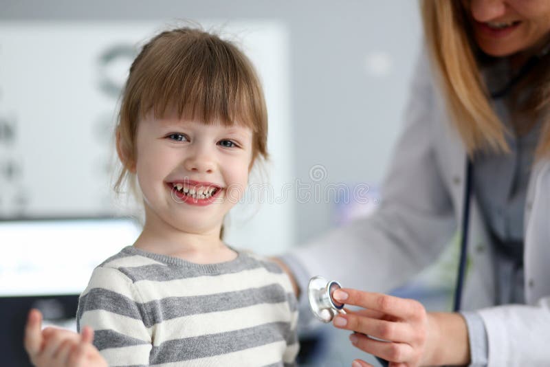 Menina bonito de sorriso com batimento card?aco de medi??o do doutor com estetosc?pio imagem de stock royalty free Menina bonito de sorriso com batimento card?aco de medi??o do doutor com estetosc?pio imagem de stock royalty free
