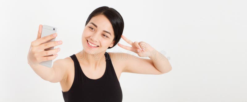 A menina bonito do sorriso moderno faz o sinal de paz dos dedos do selfie e da mostra dois foto de stock A menina bonito do sorriso moderno faz o sinal de paz dos dedos do selfie e da mostra dois foto de stock