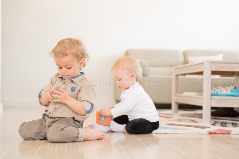 Menina bonito e menino que jogam com brinquedos em casa imagem de stock Menina bonito e menino que jogam com brinquedos em casa imagem de stock