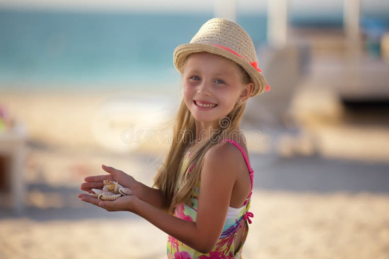 Menina bonito na praia que está nas mãos de um shell fotos de stock royalty free Menina bonito na praia que está nas mãos de um shell fotos de stock royalty free