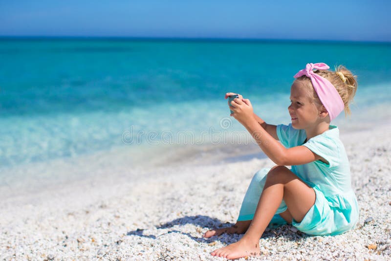 Menina bonito pequena que toma imagens no telefone em foto de stock Menina bonito pequena que toma imagens no telefone em foto de stock