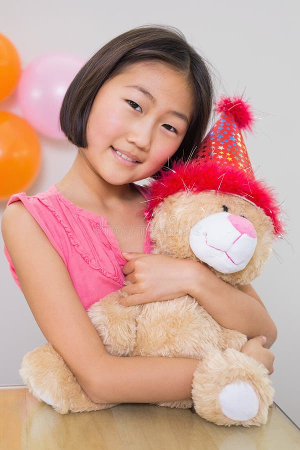 Menina bonito que abraça o brinquedo macio em uma festa de anos fotografia de stock royalty free Menina bonito que abraça o brinquedo macio em uma festa de anos fotografia de stock royalty free
