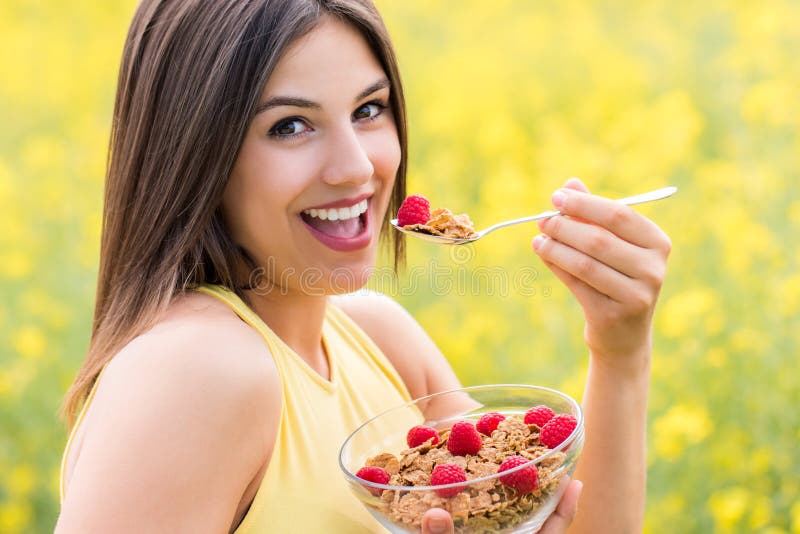 Menina bonito que come o café da manhã saudável do cereal fora imagem de stock Menina bonito que come o café da manhã saudável do cereal fora imagem de stock