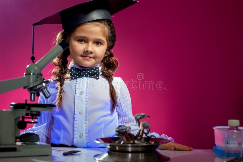 Image of cute girl posing in graduate hat, on pink backdrop. Image of cute girl posing in graduate hat, on pink backdrop