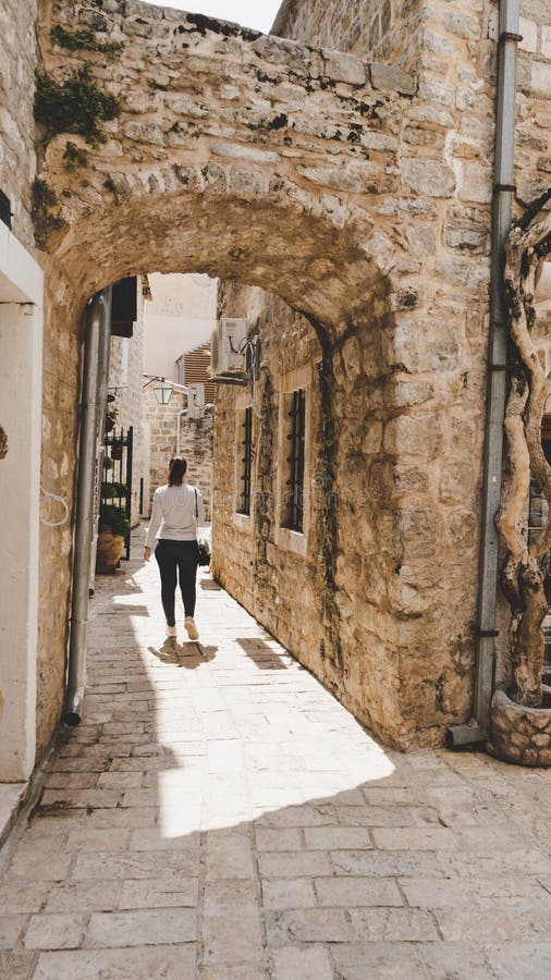 Menina branca nova que toma imagens nas ruas estreitas pequenas da cidade velha de Budva, Montenegro Mulher que anda entre mediev imagens de stock Menina branca nova que toma imagens nas ruas estreitas pequenas da cidade velha de Budva, Montenegro Mulher que anda entre mediev imagens de stock