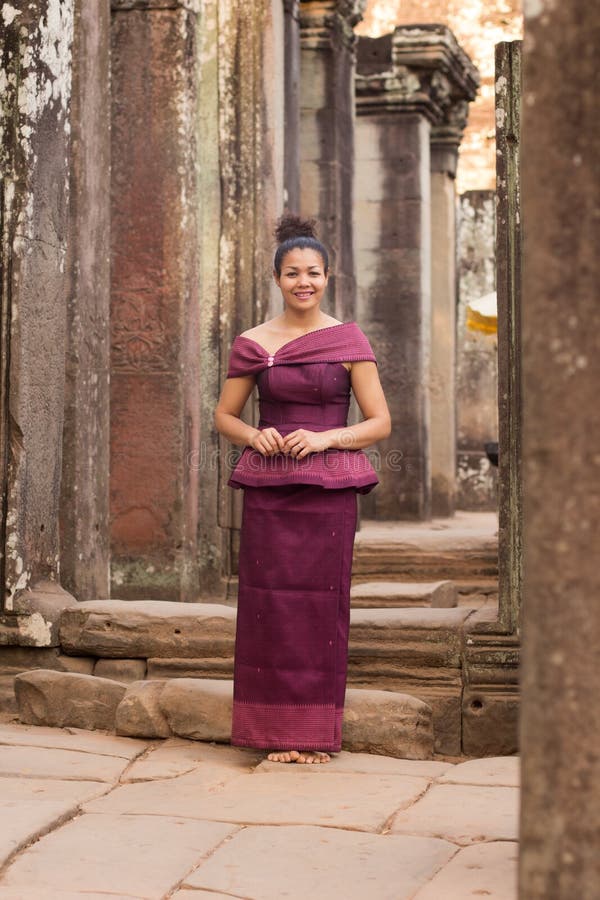 Menina cambojana no vestido do Khmer que está no templo de Bayon na cidade de Angkor imagens de stock Menina cambojana no vestido do Khmer que está no templo de Bayon na cidade de Angkor imagens de stock