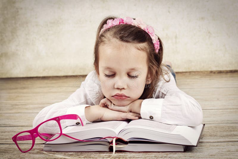 Menina cansado pequena que dorme nos livros foto de stock royalty free Menina cansado pequena que dorme nos livros foto de stock royalty free