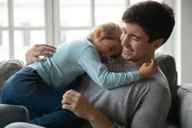 Sorridente menina deitada no sofá confortável, gostando de jogar