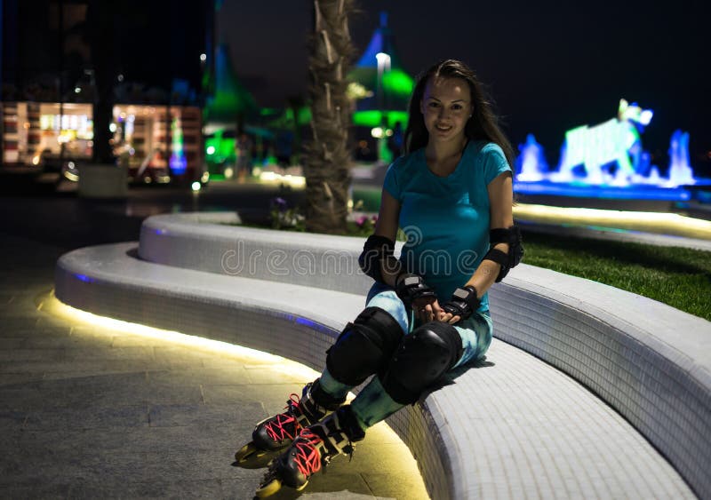 A menina caucasiano aprecia a patinagem de rolo na cidade da noite com luzes no bokeh fotografia de stock A menina caucasiano aprecia a patinagem de rolo na cidade da noite com luzes no bokeh fotografia de stock
