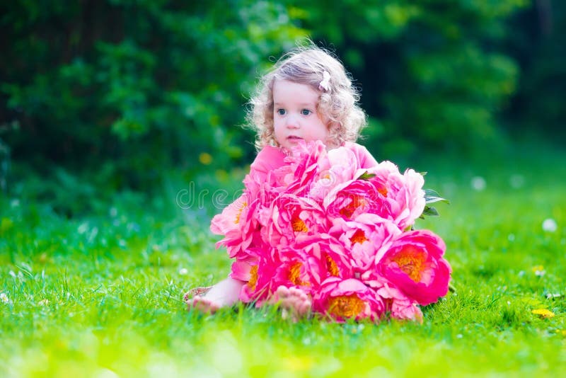 Menina com as flores da peônia no jardim fotografia de stock Menina com as flores da peônia no jardim fotografia de stock