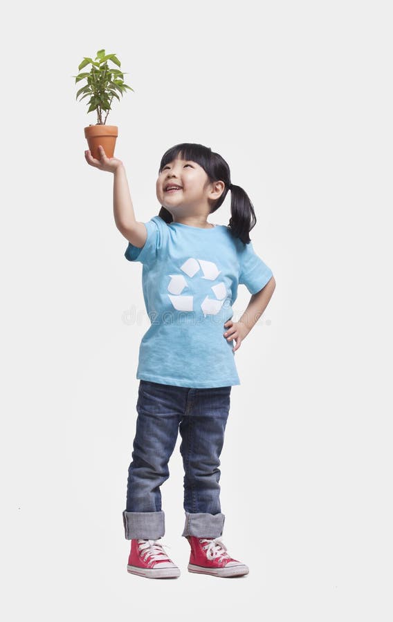 Menina com as tranças em recicl o t-shirt do símbolo que guardara a planta em pasta acima de sua cabeça, tiro do estúdio imagens de stock Menina com as tranças em recicl o t-shirt do símbolo que guardara a planta em pasta acima de sua cabeça, tiro do estúdio imagens de stock