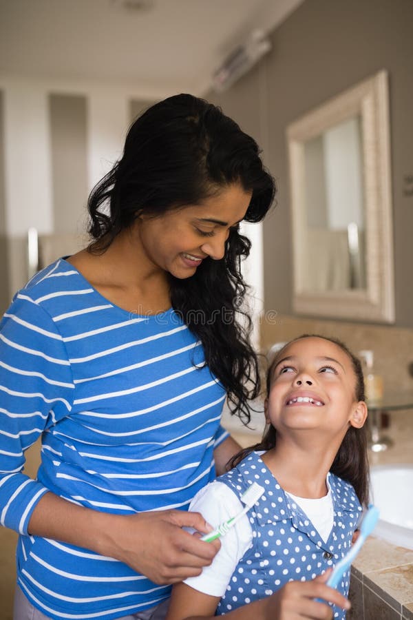 Menina com a mãe que guarda escovas de dentes no banheiro fotos de stock Menina com a mãe que guarda escovas de dentes no banheiro fotos de stock