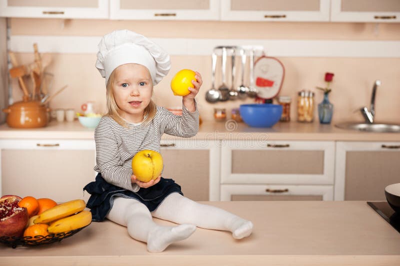 Menina com o chapéu do cozinheiro chefe que guarda frutos quando fotografia de stock Menina com o chapéu do cozinheiro chefe que guarda frutos quando fotografia de stock