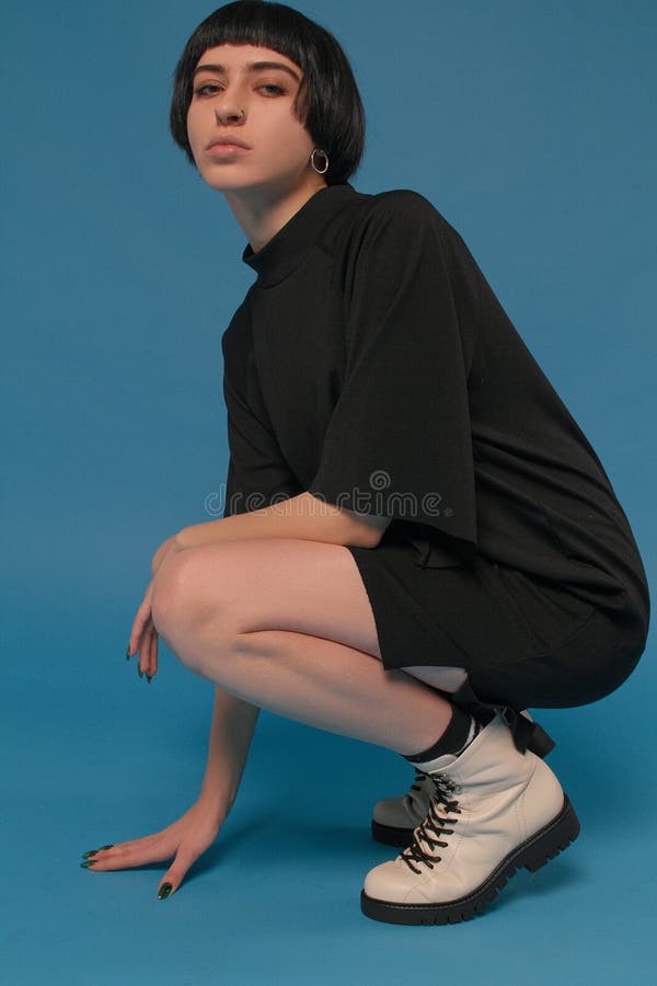 Menina com pés bonitos em sapatas da forma em um fundo azul foto de stock Menina com pés bonitos em sapatas da forma em um fundo azul foto de stock