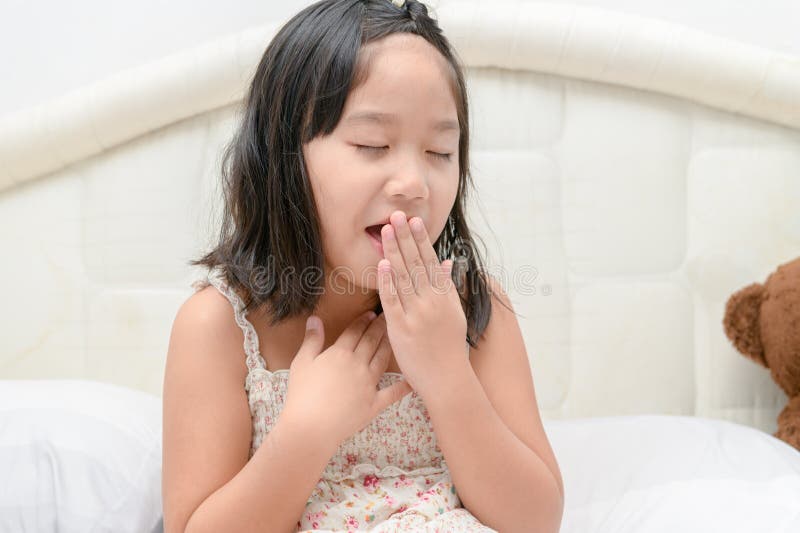 Menina com a tosse e a garganta inflamada que sentem doentes na cama imagem de stock Menina com a tosse e a garganta inflamada que sentem doentes na cama imagem de stock