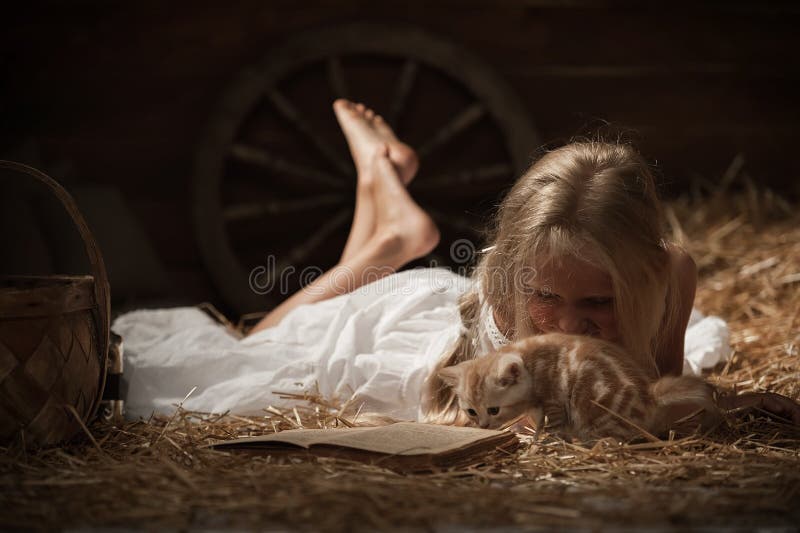 Menina com um gatinho no feno imagem de stock royalty free Menina com um gatinho no feno imagem de stock royalty free