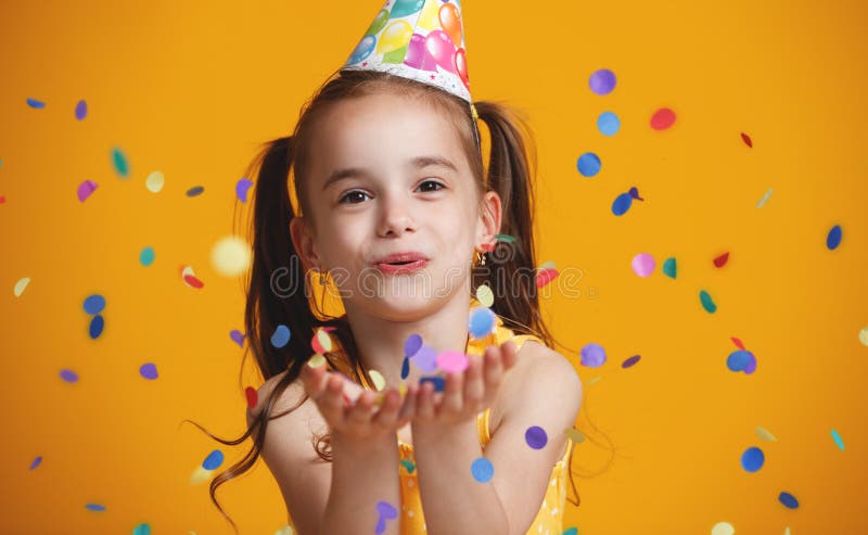 Menina da criança do feliz aniversario com confetes no fundo amarelo fotografia de stock royalty free Menina da criança do feliz aniversario com confetes no fundo amarelo fotografia de stock royalty free
