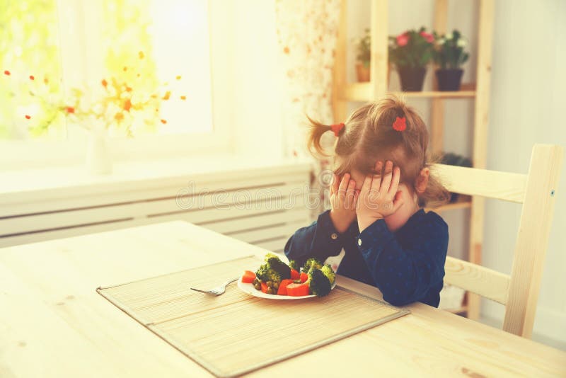 A menina da criança não gosta e não os quer de comer de vegetais