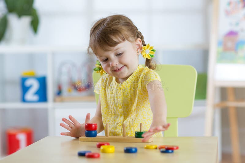 A menina da criança pequena joga no jardim de infância na classe do pré-escolar de Montessori fotografia de stock A menina da criança pequena joga no jardim de infância na classe do pré-escolar de Montessori fotografia de stock