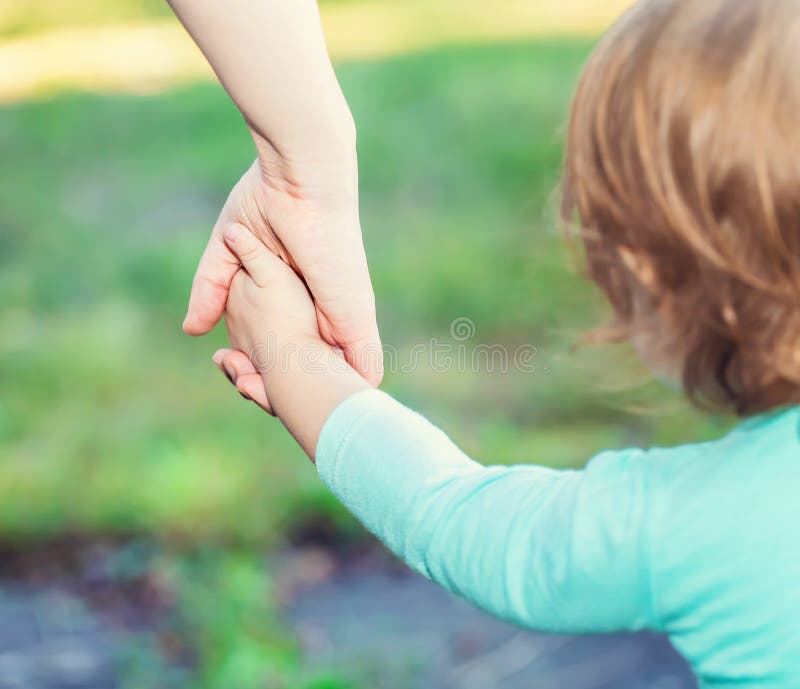 Menina da criança que guarda as mãos com seu pai