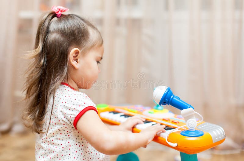 Menina da criança que joga em um piano do brinquedo foto de stock royalty free Menina da criança que joga em um piano do brinquedo foto de stock royalty free