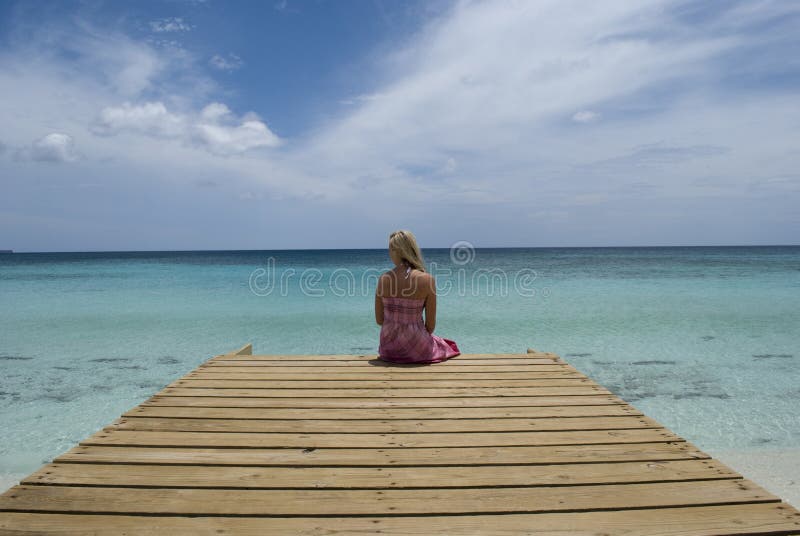 Picture of a woman sitting on a dock overlooking the Caribbean. Shot at Bahia de Las Aguilas in the Dominican Republic. Picture of a woman sitting on a dock overlooking the Caribbean. Shot at Bahia de Las Aguilas in the Dominican Republic.