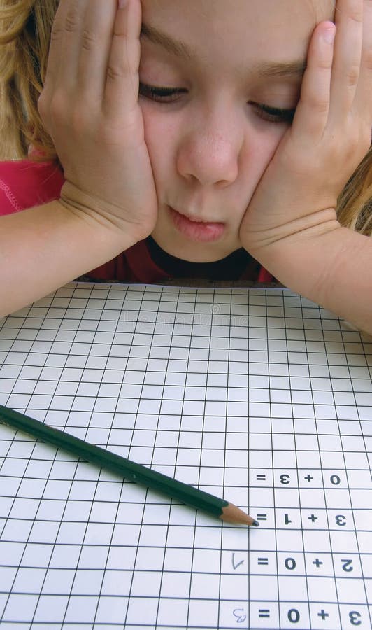 Portrait of a concerned young girl who has a problem with solving math homework. She put her head between his hands, sad, worried because she do not know to solve the task. Vertical color photo. Portrait of a concerned young girl who has a problem with solving math homework. She put her head between his hands, sad, worried because she do not know to solve the task. Vertical color photo.