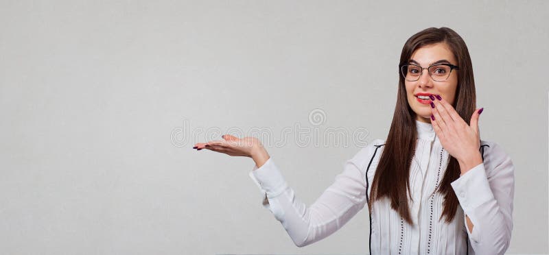 A menina da morena aponta a um fundo cinzento fotografia de stock A menina da morena aponta a um fundo cinzento fotografia de stock