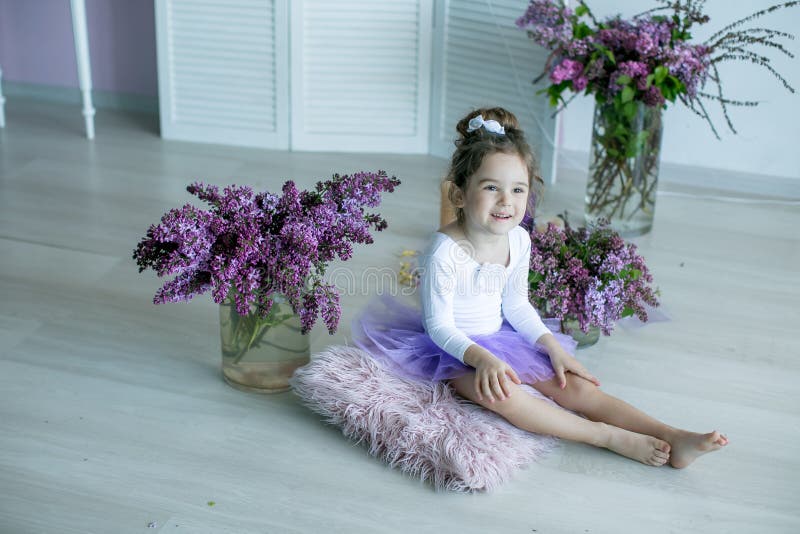 Menina De 4 a 6 Anos Sentada Sobre Um Travesseiro Em Uma Saia Roxa Cercada  Por Flores Lilás Foto de Stock - Imagem de quarto, imagem: 165705164