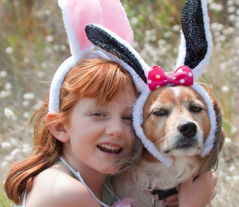 A menina de cabelo vermelha pequena com cão de estimação vestiu-se acima nas orelhas do coelhinho da Páscoa imagens de stock royalty free A menina de cabelo vermelha pequena com cão de estimação vestiu-se acima nas orelhas do coelhinho da Páscoa imagens de stock royalty free