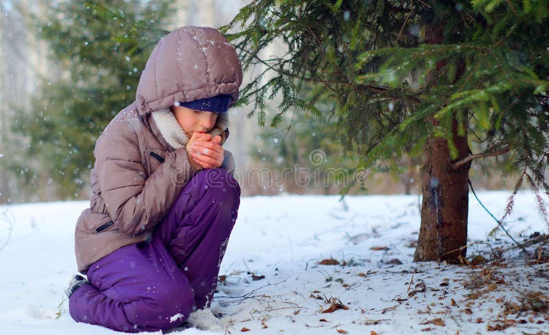 Menina de congelação triste que tenta ficar morno na floresta do inverno