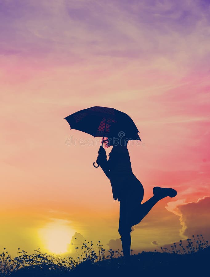 Menina de salto do guarda-chuva do borrão de movimento com silhueta do por do sol imagens de stock royalty free Menina de salto do guarda-chuva do borrão de movimento com silhueta do por do sol imagens de stock royalty free