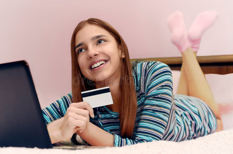 A menina de sorriso bonita nova faz a compra em linha usando o portátil imagem de stock royalty free A menina de sorriso bonita nova faz a compra em linha usando o portátil imagem de stock royalty free