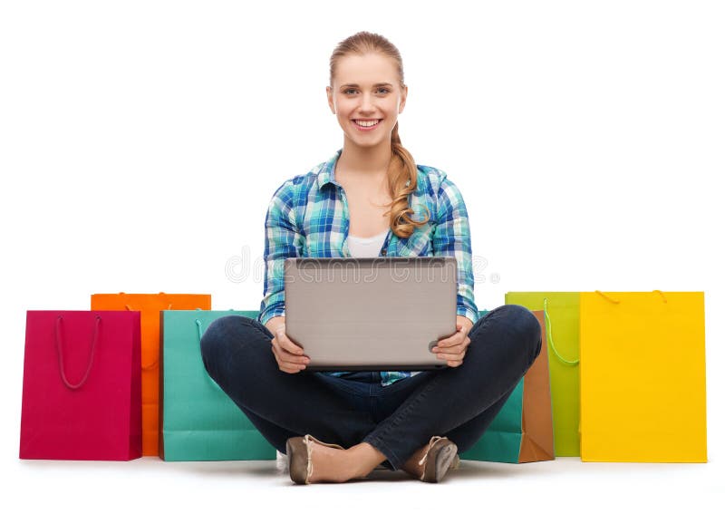 Rapariga sorridente com portátil e sacos de compras foto de stock