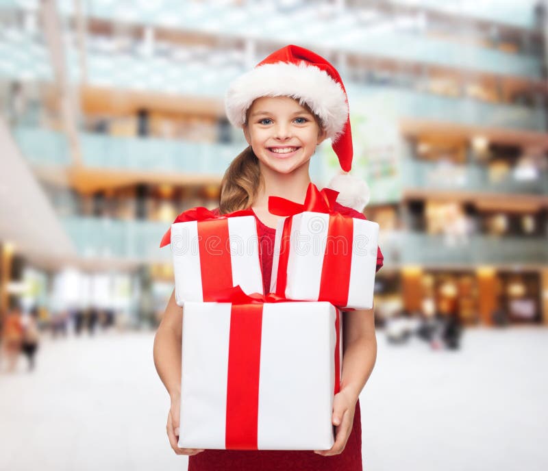 Menina de sorriso no chapéu do ajudante de Santa com presentes foto de stock Menina de sorriso no chapéu do ajudante de Santa com presentes foto de stock