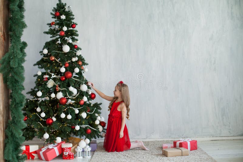 A menina decora presentes de uma casa de férias do ano novo de árvore de Natal foto de stock A menina decora presentes de uma casa de férias do ano novo de árvore de Natal foto de stock