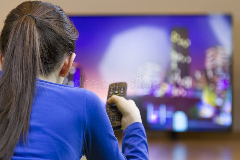 Menina do adolescente com controlo a distância que olha a tevê esperta fotografia de stock Menina do adolescente com controlo a distância que olha a tevê esperta fotografia de stock