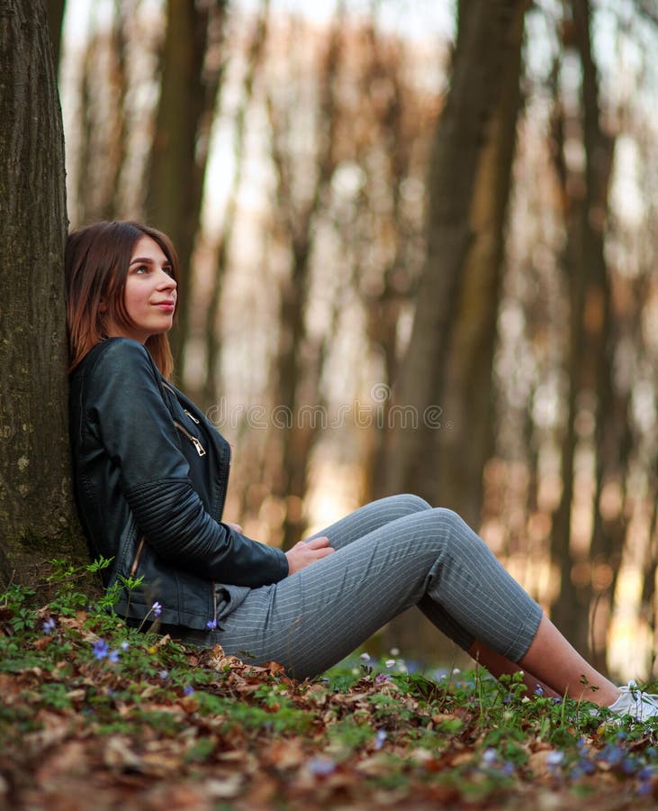 Menina do jovem adolescente na floresta de florescência da mola no fundo das árvores e do por do sol fotografia de stock royalty free Menina do jovem adolescente na floresta de florescência da mola no fundo das árvores e do por do sol fotografia de stock royalty free