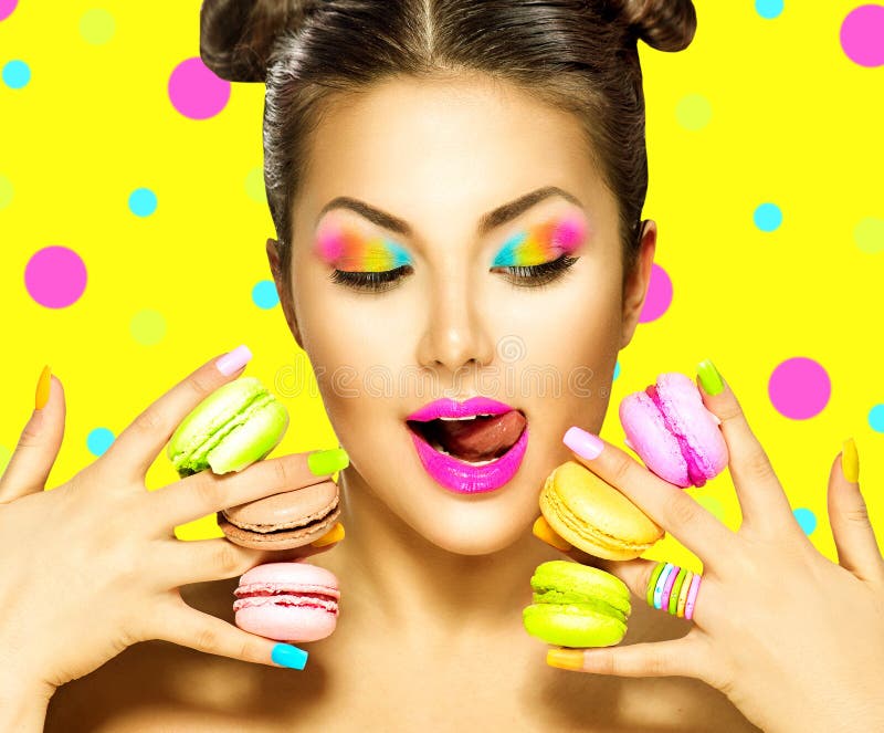 Menina do modelo de forma da beleza que toma bolinhos de amêndoa coloridos foto de stock