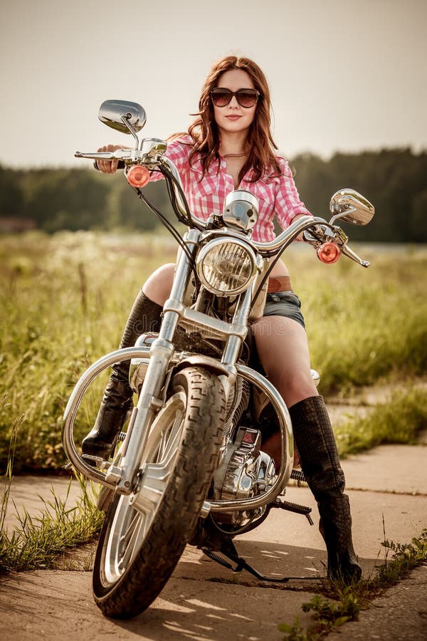 Menina do motociclista que senta-se na motocicleta imagens de stock royalty free Menina do motociclista que senta-se na motocicleta imagens de stock royalty free