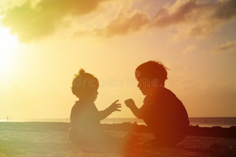 Menina do rapaz pequeno e da criança que joga no por do sol imagens de stock royalty free Menina do rapaz pequeno e da criança que joga no por do sol imagens de stock royalty free