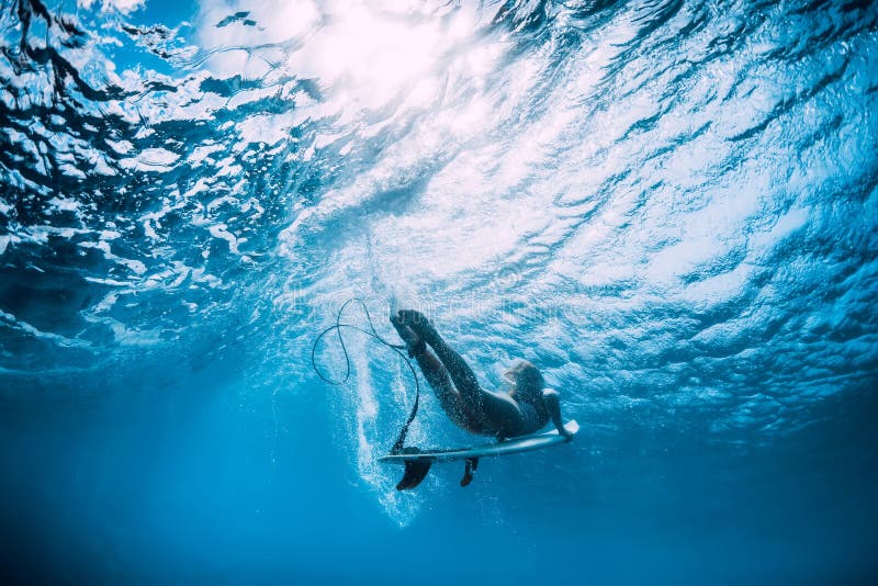 Surfer girl with surfboard dive underwater under wave. Surfer girl with surfboard dive underwater under wave