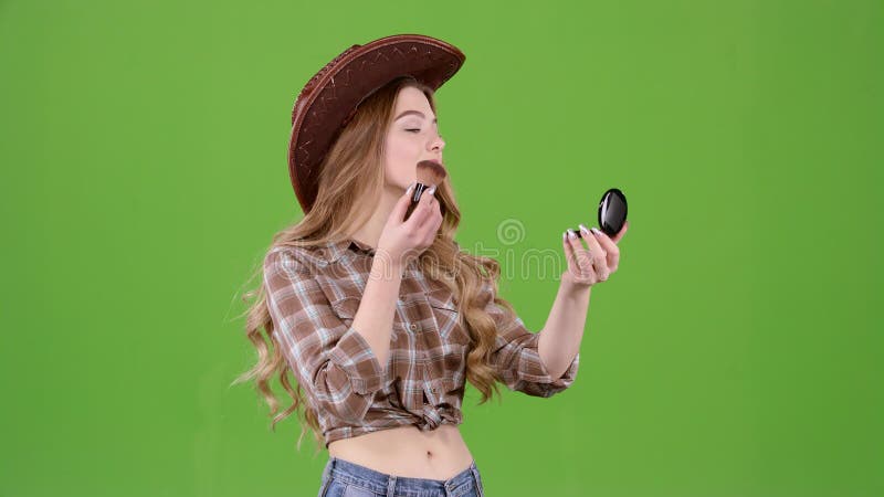 A menina do vaqueiro está guardando uma escova e está pulverizando sua cara Tela verde