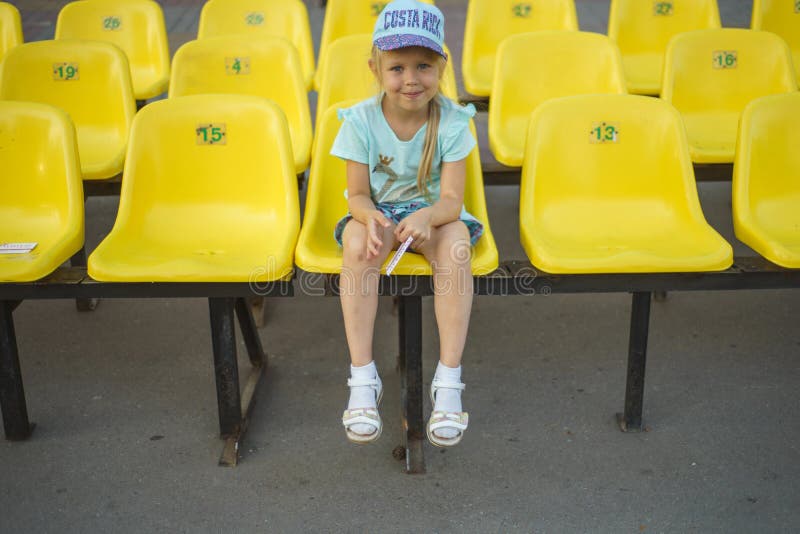 Menina em assentos amarelos do estádio foto de stock Menina em assentos amarelos do estádio foto de stock