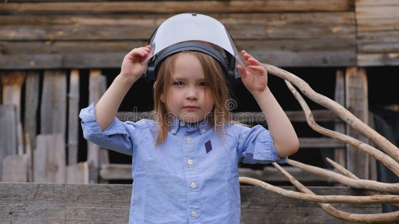 A menina em um capacete protetor de um construtor ou de um coordenador joga um super-herói