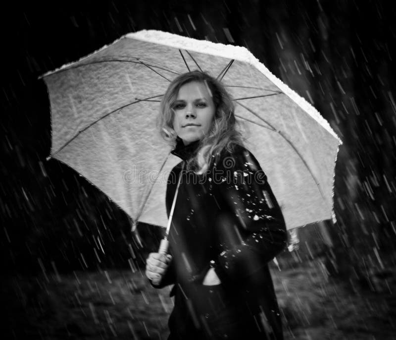 Menina em um revestimento preto e em um guarda-chuva branco que anda abaixo da rua muito em umas nevadas fortes fotografia de stock Menina em um revestimento preto e em um guarda-chuva branco que anda abaixo da rua muito em umas nevadas fortes fotografia de stock